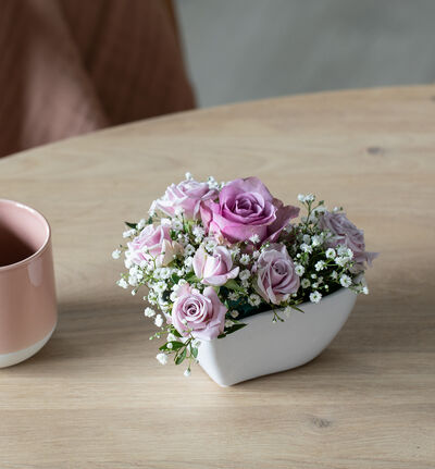 Lilla og rosa blomster i hjerteskål med bamse